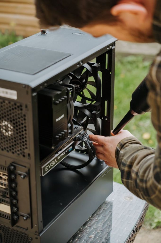 Using a can of compressed air with a straw nozzle to blow dust from a laptop vent