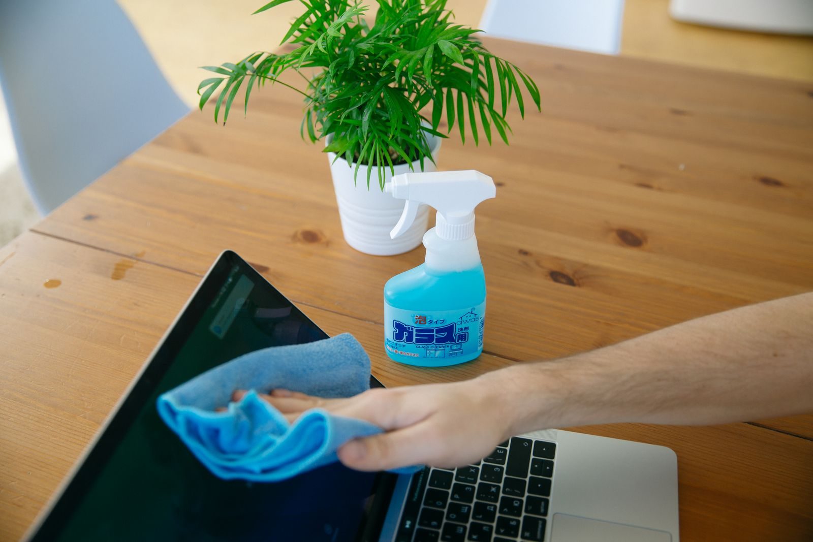 Wiping a laptop screen with a microfiber cloth for a streak-free finish