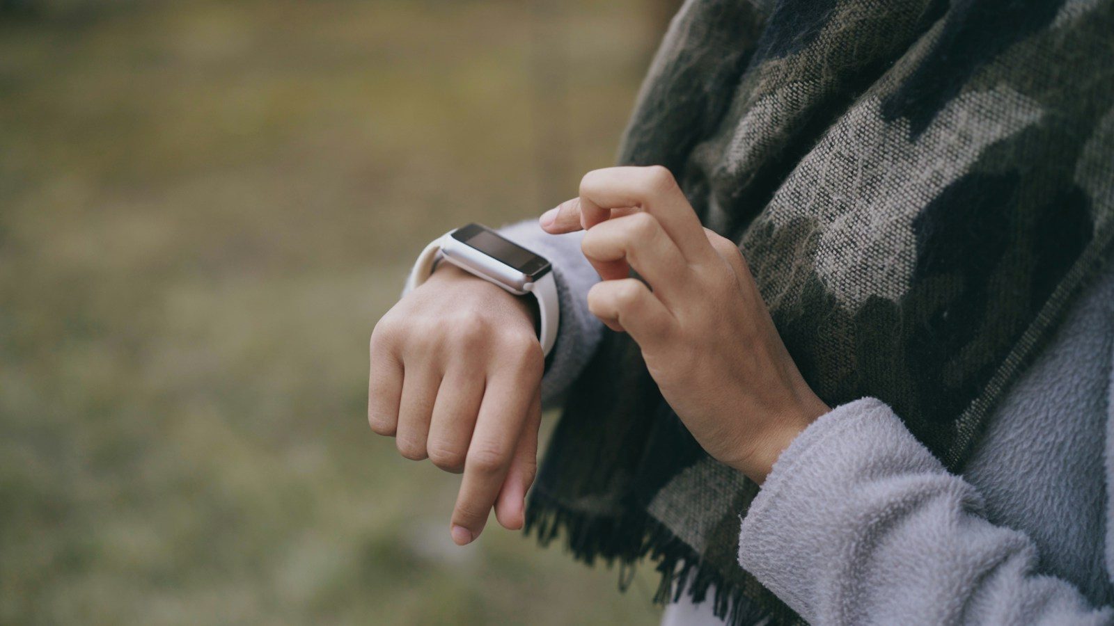 Runner checking a smartwatch while jogging outdoors at sunrise.